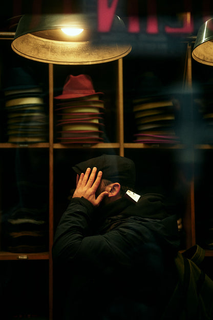 On a rainy Soho walk November 2023 I stumbled upon the tiniest hat shop I've seen. Looking through the window I saw this man trying on a hat. The overhead light made the atmosphere super moody so had to make this photo.